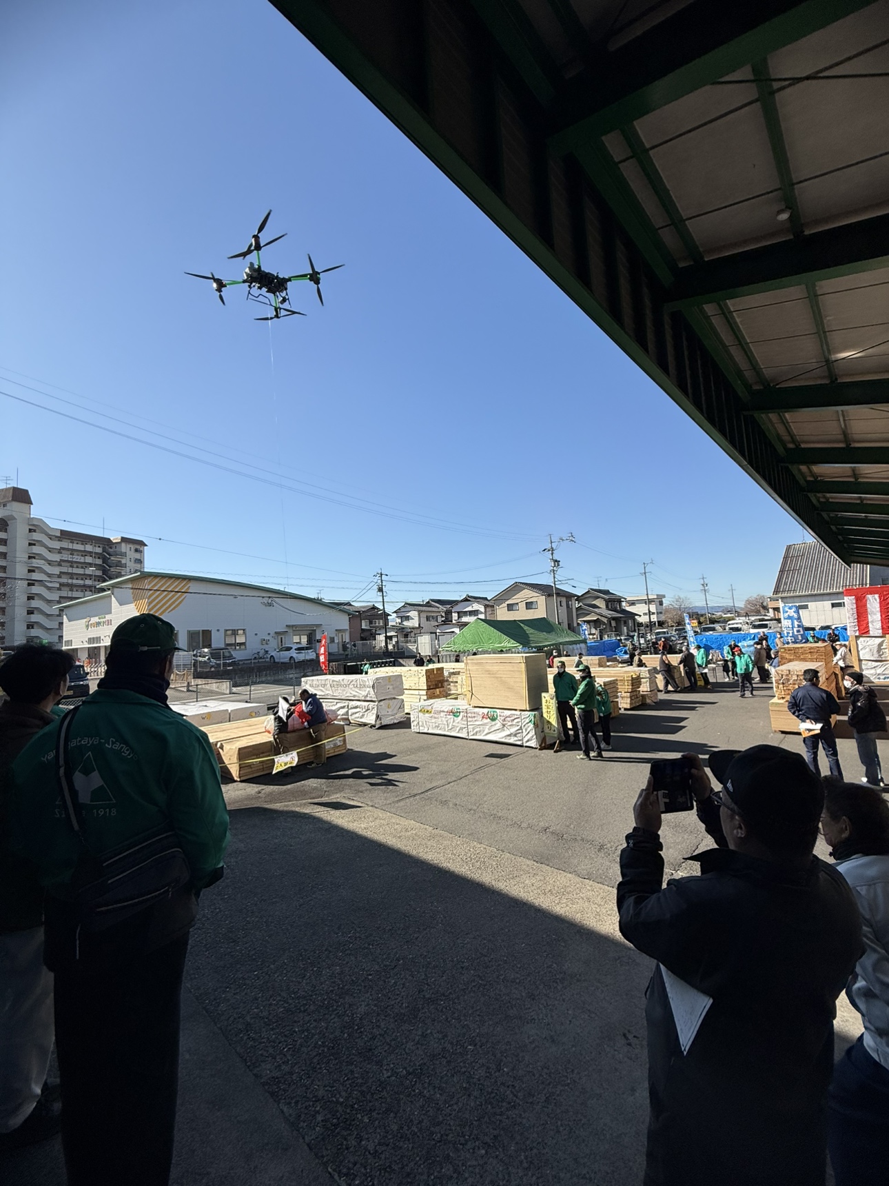 空高く舞い上がるドローンを社員もおお客様も見守っています。